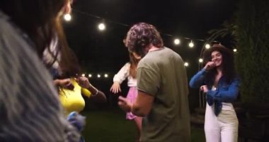 Partide arka bahçede dans eden çok ırklı gençlerin çoğu. Kafkasyalı neşeli kız ve erkek dışarıda eğleniyor. Afro-Amerikalı kadın, oğlanla dans ediyor. Yaz partisi kutlaması. Boş zaman konsepti