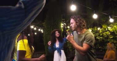 Partide arka bahçede dans eden mutlu çoklu etnik gençler. Afro-Amerikalı bir kız ve beyaz bir adamın açık havada eğlenirken portresi. Güzel dişiler ve yakışıklı oğlanlar dans eder. Eğlenceli konsept