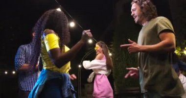 Afro-Amerikalı kız ve beyaz adamın açık havada eğlenip dans edişinin portresi. Neşeli melez genç arkadaşlar partide müzik dinliyorlar. Güzel dişiler ve yakışıklı oğlanlar dans eder. Parti konsepti