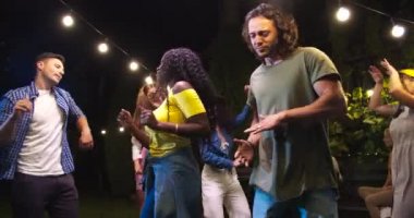 Mutlu Afrikalı Amerikalı kız ve beyaz oğlan dışarıda eğleniyor ve dans ediyor. Neşeli melez genç arkadaşlar bahçede bir partide müzik dinliyorlar. Şapka danslarında güzel bir kadın. Parti konsepti
