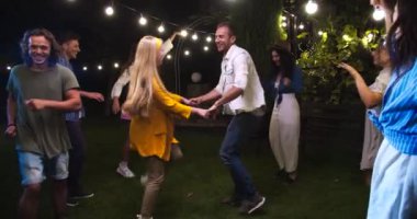 Neşeli melez genç erkekler ve kadınlar bahçe partisinde müzik dinlemeye gidiyorlar. Güzel beyaz kız ve yakışıklı oğlan eğleniyor ve dans ediyor. Gülümseyen güzel bir Asyalı kadın. Açık hava konsepti