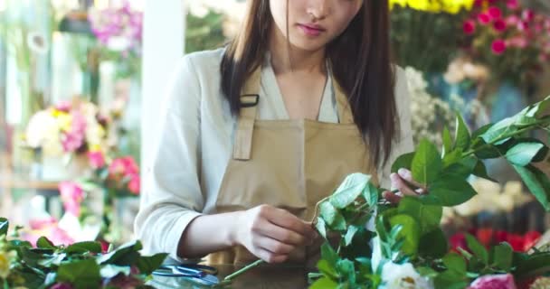 Çiçekçide çalışan Asyalı çekici kadın çiçekçiye yakın çekim. Çiçek açan ve gül sapları kesen güzel kadın işçilerin nazik elleri. İş ve çalışma süreci kavramı. — Stok video