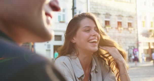 Close up retrato de alegre bela jovem fêmea sorrindo para falar com amigos de bom humor na cidade. Joyful masculino e feminino conversando e rindo ao ar livre. Estilo urbano. Conceito de conversação — Vídeo de Stock