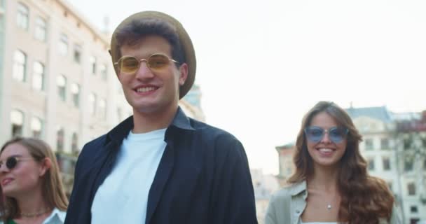 Retrato de um sorridente feliz e raparigas de pé na rua. Bonito homem caucasiano de chapéu na cidade de bom humor. Menina bonita adiando óculos de sol com sorriso no rosto ao ar livre. Conceito urbano — Vídeo de Stock