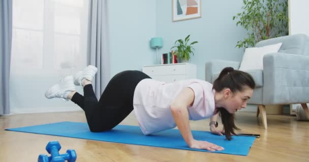 Plan lateral medio de chica en forma joven haciendo ejercicio de fitness y ejercicios de flexiones para un estilo de vida hermoso y manos fuertes en la sala de estar. Vida sana y deportiva. Formación, entrenamiento y bienestar. — Vídeos de Stock