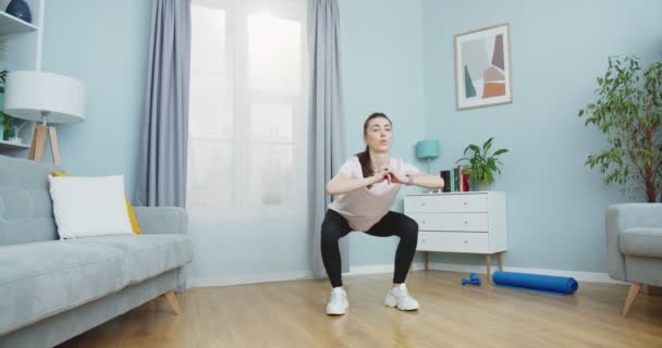 건강 한 여성이 건강을 위해 운동을 하고 집 거실에서 건강 한 생활을 위해 일어나 운동을 하는 중간 계획이다. 운동과 체력. 훈련, 작업 및 건강에 대한 개념. — 비디오