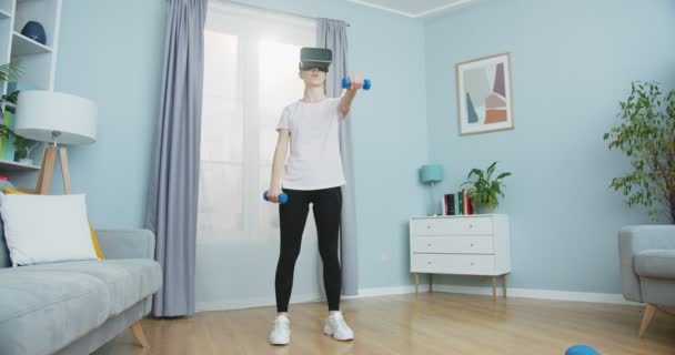 Plan intermédiaire de la fille en réalité virtuelle lunettes de formation à la maison en utilisant des haltères et profiter ar. Style de vie sain et concept de simulation vr. Sport et fitness. Formation, entraînement et bien-être. — Video