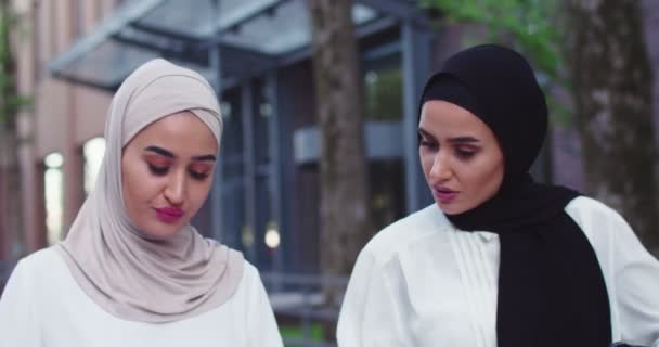 Close up de duas mulheres de negócios Aribic em lenços de cabeça tradicionais andando e discutindo documentos falando, beber café. Colegas profissionais discutindo cooperação. Trabalho em equipe, negócios, estilo de vida. — Vídeo de Stock