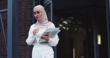 Kendine güveni tam Müslüman bir kadın gözlüğünü çıkarıyor ve üniversite bahçesinde tablet ve kağıtlarla yürüyor. Avrupa 'da okuyan genç bir göçmen kadın. Modern Orta Doğulu bayan yurtdışında eğitimin tadını çıkarıyor