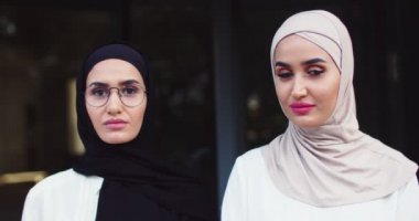 Geleneksel başörtüsü ve kameraya bakan gözlüklü iki genç Arap kadının portresini yakından çek. Caddede tesettürlü oldukça neşeli Müslüman kadınlar. İslami cazibeli mutlu bayanlar