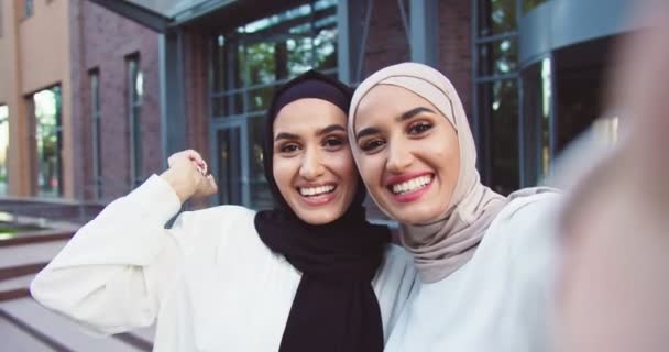 POV dwóch muzułmańskich muzułmanek rozmawiających z kamerą podczas nagrywania video. Samice Arabians nagrywają, machają ręką i uśmiechają się. Piękne kobiety mówiące w kamery na zewnątrz. — Wideo stockowe