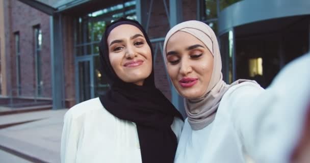 POV of two Arabs muslim women talking to camera when having videochat. Females Arabians videochatting, waving with hand and smiling. Beautiful women speaking in webcam outdoors. — Stock Video