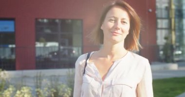 Güneşli bir günde okulun önünde dikilen mutlu güzel bayanı kapatın. Neşeli, beyaz, güzel bir kadın. Şehirde, güneş ışığında iyi bir ruh hali içinde. Olumlu duygular. Portre konsepti