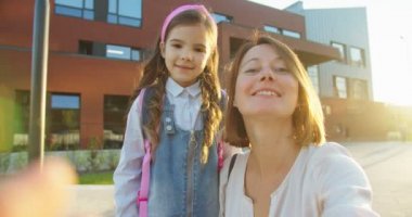Güneşli bir günde web kameralarında gülümseyen ve konuşan neşeli anne-kız POV 'u. Sevimli, küçük liseli kızla sohbet eden ve sokakta el sallayan neşeli beyaz bir kadın. Konsepti kapat