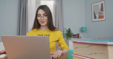 Gözlüklü mutlu güzel kız evde oturmuş keyfi yerindeyken dizüstü bilgisayarı açıp interneti arıyor. Kafkasyalı neşeli bir kadın rahat bir odada bilgisayarda geziniyor. Boş zaman konsepti