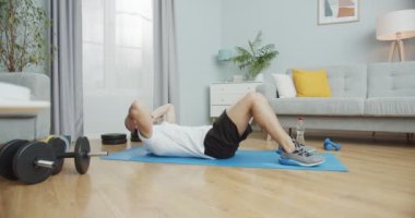 Kafkas atleti egzersiz yapıyor, özünü güçlendiriyor, kablosuz kulaklıkla müzik dinliyor. Spor kıyafetli bir adam karın kasları üzerinde çalışıyor, hasırın üstünde mekik çekiyor. Sağlık ve spor konsepti.