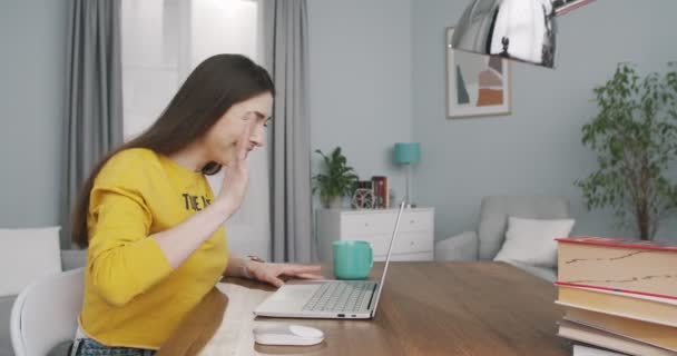 Zijaanzicht van vrolijke mooie blanke jonge vrouw zwaaiend met haar hand en pratend op video op laptop in de kamer. Portret van gelukkig mooi meisje glimlachend terwijl ze video chat op de computer. Beginbegrip — Stockvideo