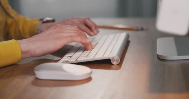 Gros plan de femmes caucasiennes tapant sur le clavier et utilisant la souris d'ordinateur tout en étant assis dans la pièce à la maison. Les doigts de la femme tapant sur le clavier tout en travaillant à l'intérieur. Concept technologique — Video