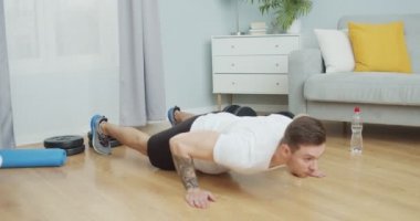 Çevrimiçi spor antrenmanı yapan güçlü atletik erkek, evde izole bir şekilde yaşıyor. Genç Kafkas sporcusu vücut geliştirme için spor yapıyor, şınav çekiyor. Spor, sağlık, sağlık konsepti.