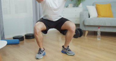 Kaslı bir sporcuyu iç mekan antrenmanı yaparken, bacakları çömelmiş bir şekilde kapat. Güçlü bir erkek antrenmanı, oturma odasındaki kalça kaslarını geliştirmek için bacak kasları. Sağlık ve zengin yaşam tarzı konsepti.