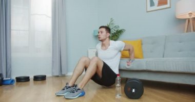 Güçlü bir atletik adam spor yapıyor, antrenman yapıyor, evde izole halde. Kafkasyalı genç bir erkek vücut geliştirmek için ters şınav çekiyor. Spor ve spor. Sağlık hizmeti, sağlık konsepti.