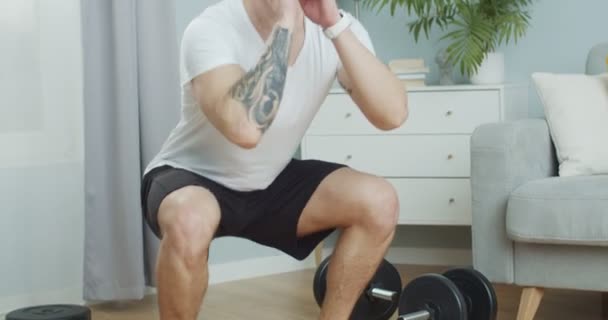 Sluit een sportman die sport doet, spring squat dijen workout thuis. Een sterke mannelijke training, het spreiden van beenspieren om de billen in de woonkamer te verstevigen. Gezondheidszorg en welvarend leefstijlconcept. — Stockvideo