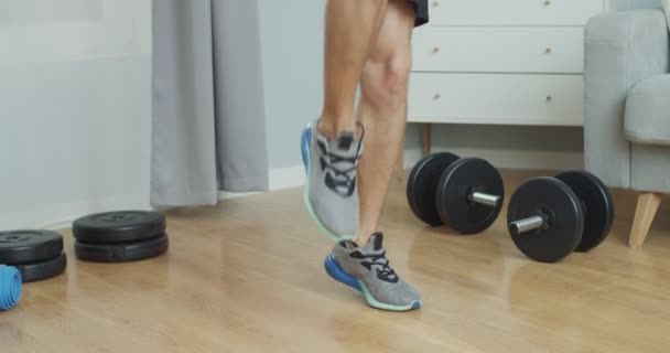 Un instructeur de fitness caucasien qui s'entraîne à la maison. Jeune homme en forme faisant des exercices cardio-intensifs genoux hauts pour renforcer les muscles des jambes. Santé, sport, athlétisme concept, — Video