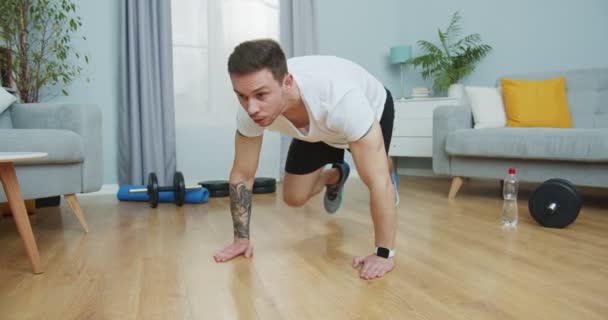 Koncentrerad passform idrottare som har cardio fitness träning, träning hemma för att hålla sig i form. Attraktiv stark man gör buken crossover rinnande planka motion. Sport, hälsa livsstil koncept. — Stockvideo