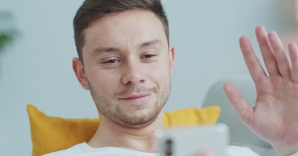 Hombre adulto feliz utilizando el teléfono inteligente para chatear con un amigo, la familia a través de una videollamada en casa. Sonriente atractivo hablando por teléfono, saludando con la mano. Relaciones a distancia, concepto de autoaislamiento — Vídeos de Stock