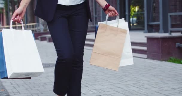 Aufgeregte kaukasische Geschäftsfrau, die mit Paketen und Papiertüten aus den Geschäften kommt. Selbstbewusste erwachsene Frau, die nach dem Einkauf mit dem Einkauf geht. Kommerz, Erfolg, Wellness-Konzept. — Stockvideo