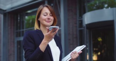 Hoş bir iş kadını sesli mesaj göndermek için akıllı telefonu kullanıyor. Yetişkin Kafkas kadın çalışanı cep telefonundan arkadaşıyla konuşuyor. Teknolojiler, iş dünyası, yönetim kavramı.
