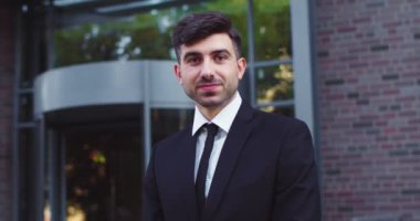 Foemal kıyafetler giyen çekici bir yetişkin adam iş bölgesinde duruyor. Beyaz erkek çalışan kameraya bakıyor ve gülümsüyor. Modern binalar. Halk, meslek, iş kavramı.