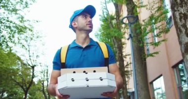 Sırt çantalı çekici genç kurye iş bölgesinde sipariş veriyor. Kafkas erkek teslimatçı, karton kutularla müşteri adresi arıyor. Hizmet, Meslek kavramı.