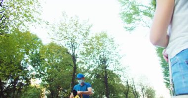 Genç beyaz erkek kurye üniforma giyiyor, müşteriye yemek getiriyor. Yüz maskeli çekici teslimatçı müşteriye emir veriyor. Hizmet, salgın, karantina, covid-19 kavramı.