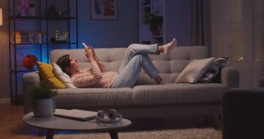 Kafkasyalı neşeli bir kadın rahat bir odada kanepede dinlenirken akıllı telefonuna yazıp dinliyormuş. Güzel, mutlu, genç bir bayan evde yatarken cep telefonuyla mesajlaşıyor. Boş zaman konsepti