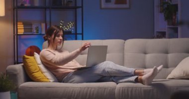 Beyaz tenli, konsantre olmuş güzel bir kadın. Oturma odasındaki kanepede dinlenirken dizüstü bilgisayarla mesajlaşıp tıklıyor. Geceleri bilgisayarda gezinen güzel genç bir bayan. Dinlenme kavramı