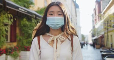 Maskeli güzel bir turistin, sokakta dikilip kameraya bakarken çekilmiş portresini yakından çek. Karantinadan sonra şehirde oldukça ciddi bir Asyalı kadın var. Koruyucu önlemler. Güvenli turizm kavramı