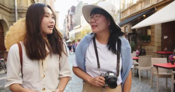 幸せなアジアの母親と娘の肖像画は、通りにスマートフォン上の翻訳アプリケーションを使用して方向を白人の美しい女性に尋ねます。携帯電話の翻訳者を介して女性と話す旅行者 — ストック動画