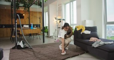 Evdeki rahat oturma odasında kirli çamaşırları toplayan mutlu, genç, güzel Asyalı kadın. Oda temizliği, ev işi, aile temizliği, yaşam tarzı..