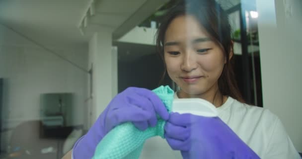 Szczęśliwy wesoły młoda piękna azjatycka kobieta próbuje otworzyć detergent czyszczący z rąk w rękawiczkach do mycia szyb. Koncepcja sprzątania, sprzątania rodziny, stylu życia. — Wideo stockowe