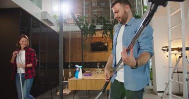 Genç ve komik çiftin eğlenmesine, dans etmesine, şarkı söylemesine, paspas ve süpürge kullanmasına, daireyi temizlerken gitar çalıyormuş gibi yapmasına yakından bakın. Mutlu çift temizliği, ev temizliği, oda temizliği..