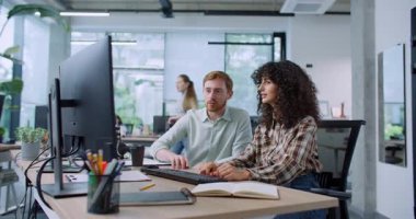 Modern ofiste omuz omuza çalışan iki Kafkas meslektaşına yaklaşan kamera. Klavyede yazan kadın. Not defterinde bir şey gösteren bir adam. Monitöre bakıyorum. Yeni stajyer kontrol ediliyor.