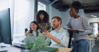 Çok ırklı bir grup insan büyük masada monitör önünde bir şey tartışıyor. Sakallı bir adam masaya değerli bilgilerle not defteri koyuyor. Herkes gülümsüyor. Takım oluşturma etkinliği.