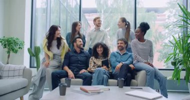 Kamera çok ırklı arkadaş grubuna yaklaşıyor. Herkes dinlenme odasındaki bir kanepenin yanında toplansın. Büyük odada kameraya poz veren mühendisler ya da programcılar. Arka planda güneşli hava.