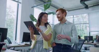 Genç ve mutlu bir kadın, iş arkadaşıyla kahve molası veriyor. Kadın elinde tablet var ve arkadaşına komik bir şey gösteriyor. İnsanlar yüksek sesle gülüyor ve pozitif eğlencenin tadını çıkarıyor..