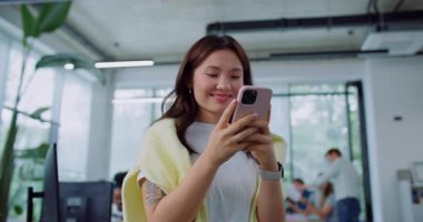 Güzel bir Asyalı kadın ofisin ortasında dururken arkadaşlarıyla ya da iş arkadaşıyla telefonda sohbet ediyor. İnternette kız mesajları var. Arka planda görülebilir insanlar birbirleriyle konuşuyorlar.