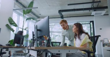 Geniş ofisteki farklı insanların yan görüşü. Yanında yakışıklı bir yönetici dururken bilgisayar kullanan çalışkan bir kadın. Meslektaşlar çalışma sorularını tartışıyorlar.