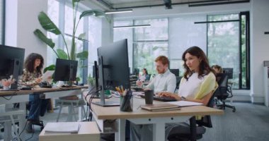 Büyük modern ofiste çalışan yoğun çeşitli yöneticilerin kamera görüntüsü. İnsanlar masalarında bilgisayarlarla oturuyorlar. Klavyeye yazı yazmak. Teknoloji cihazlarının verilerini giriyorum. İş konsepti.