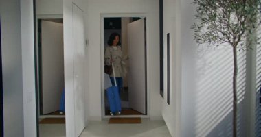 Güzel beyaz kadın kapıyı açıyor ve eve giriyor. Aynada kendine bakmak için zaman ayırıyor. Yan odaya dört tekerlek arkasında beyaz bavulla girmek. Yolculuktan döndüm..