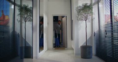 Beyaz bir erkek daireye giriyor. Küçük mavi tekerlekli bavulu sürüklerken akıllı telefon kullanan bir adam. Fuayenin ortasında duruyor. Yan odadaki bir şey dikkatimi dağıtıyor. Selamlama.